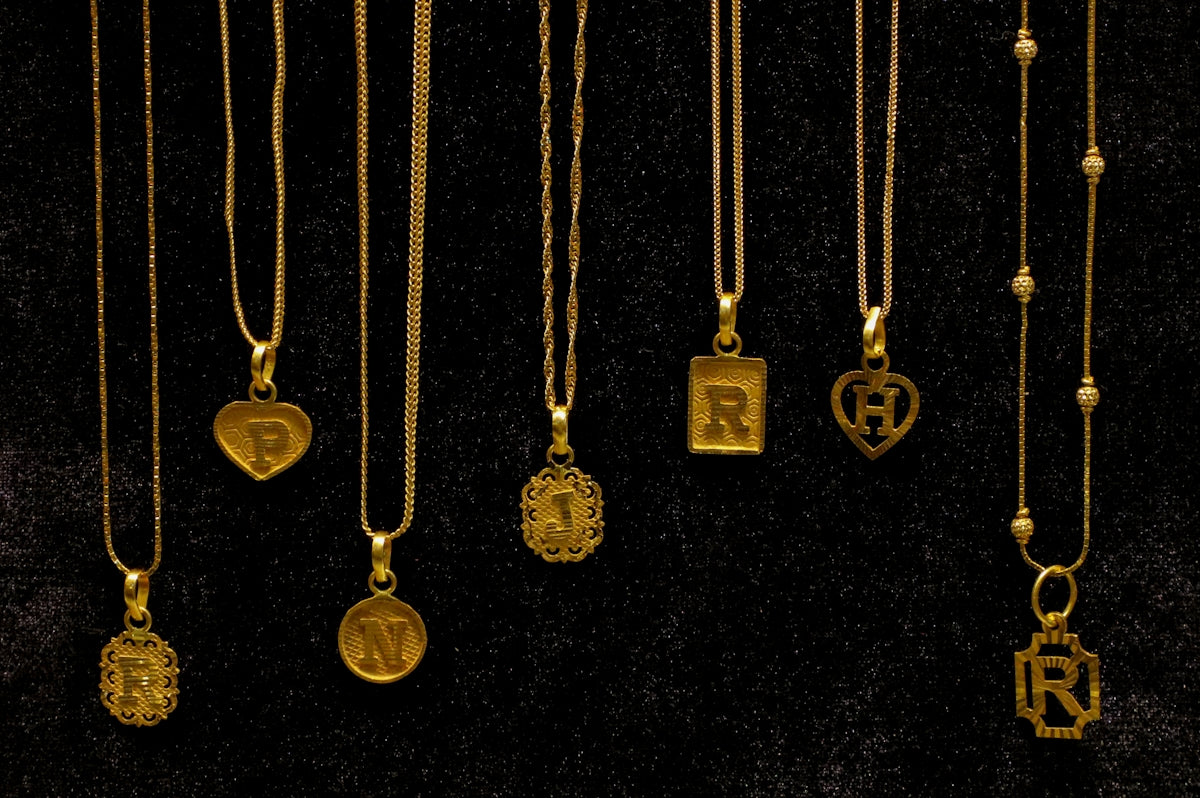 Several gold necklaces with initial pendants displayed.