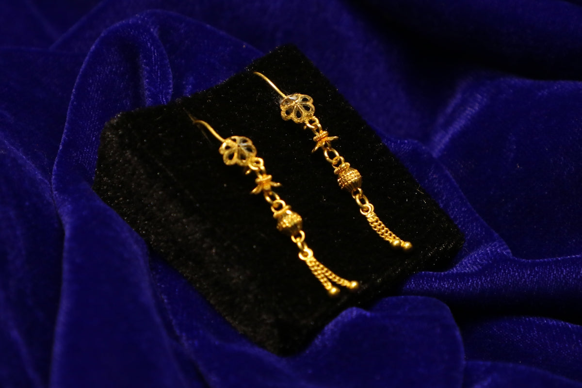 Gold dangle earrings on black velvet display