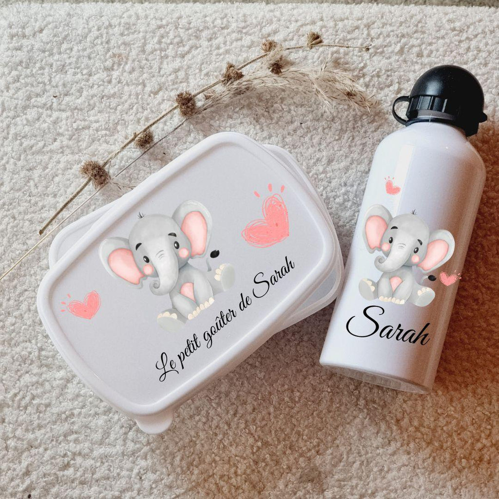 Kit de rentrée scolaire comprenant une boîte à lunch et une gourde assorties, personnalisées avec un prénom et des motifs colorés, posées sur une table en bois avec un fond lumineux.